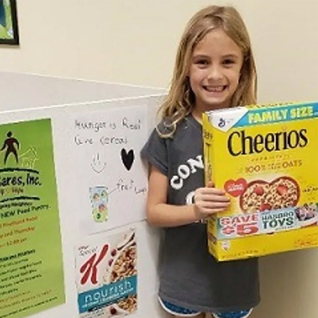 Young girl smiling with a box of Cheerios